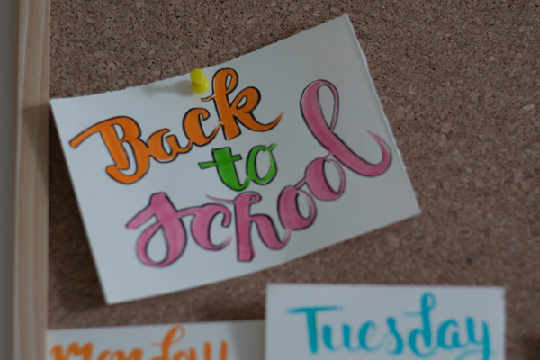 Small card pinned to cork board that says "back to school" in colourful cursive writing