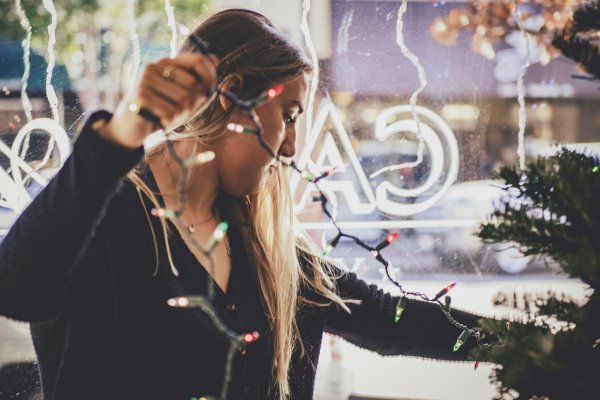 A woman inside a store putting up holiday lights